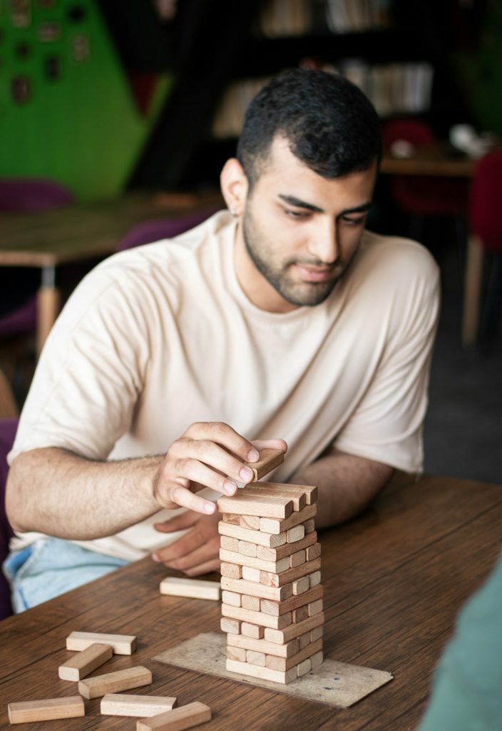 a-man-sitting-at-a-table-playing-with-wooden-blocks-pqoze5tbumw